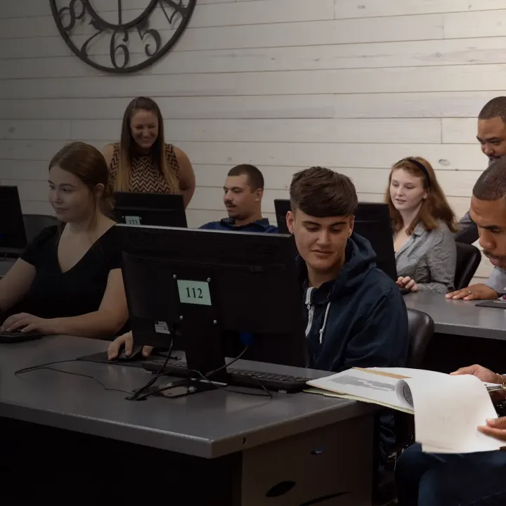 Students using a computer lab with the help of teaching staff.