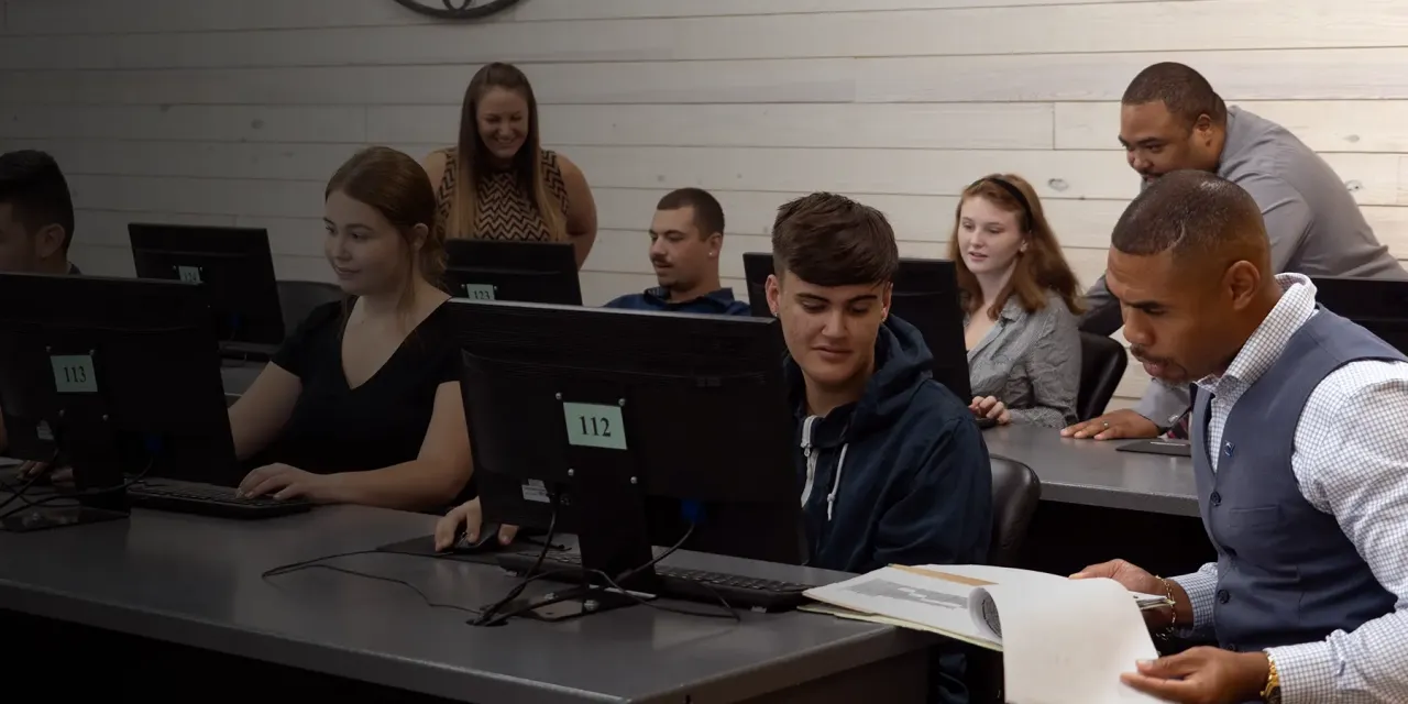 Students using a computer lab with the help of teaching staff.